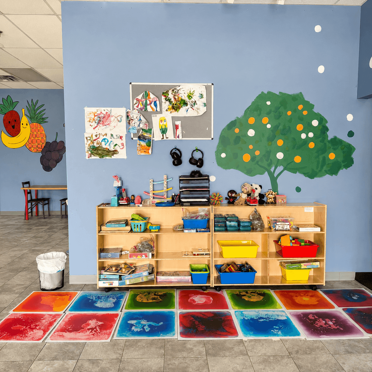 A bright, colorful playroom with soft seating, toy storage, and open floor space