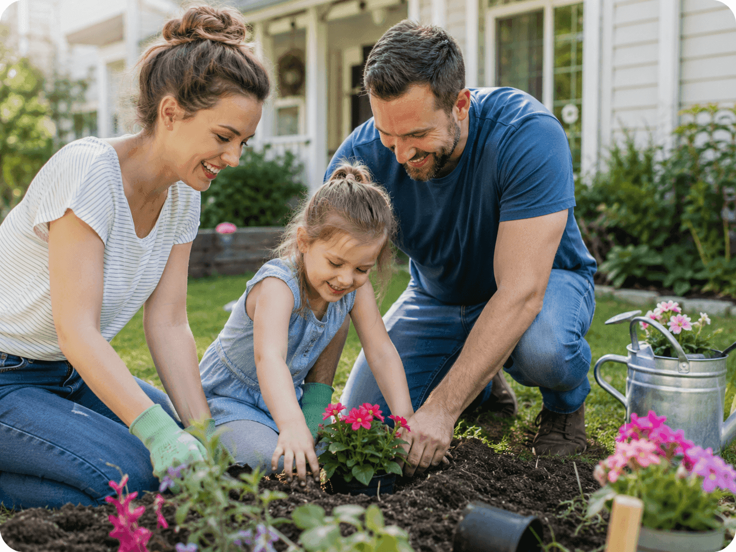 A mother, father, and young daughter planting flowers together in the garden